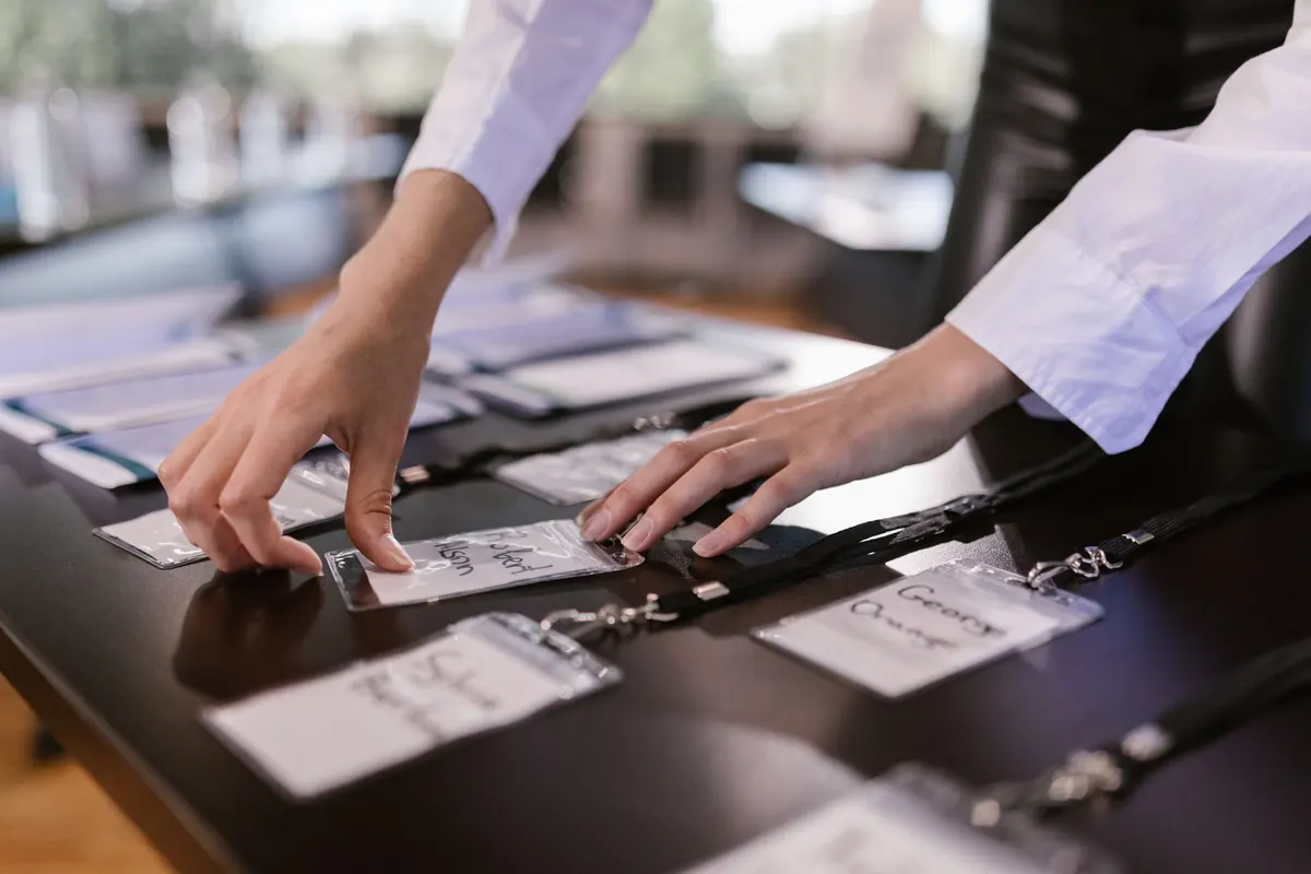 Close-up of hands arranging name tags on a conference table, preparing for a corporate event.