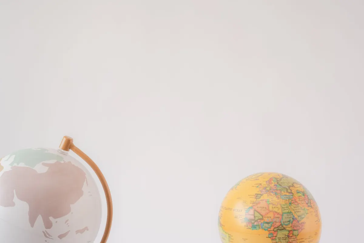 A minimalist image showcasing two globes against a light gray background offering ample copy space.