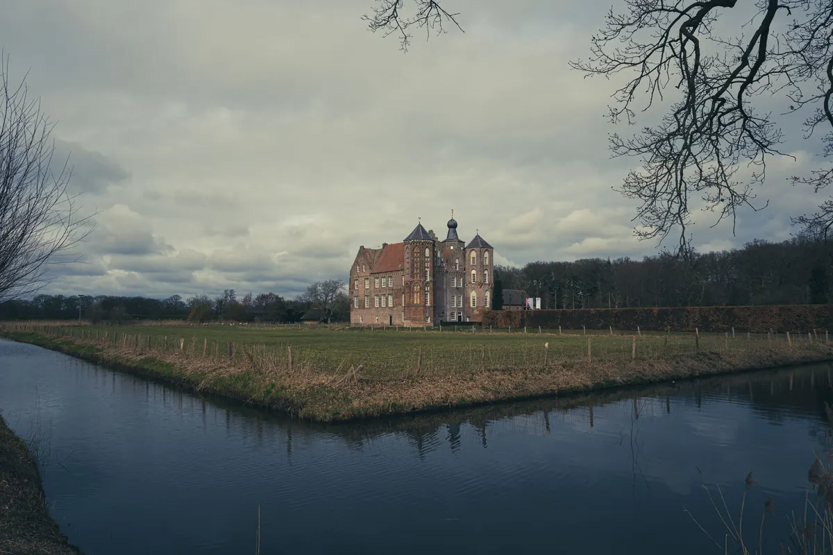 Scenic view of a historic castle in the Netherlands surrounded by a moat and rural landscape.