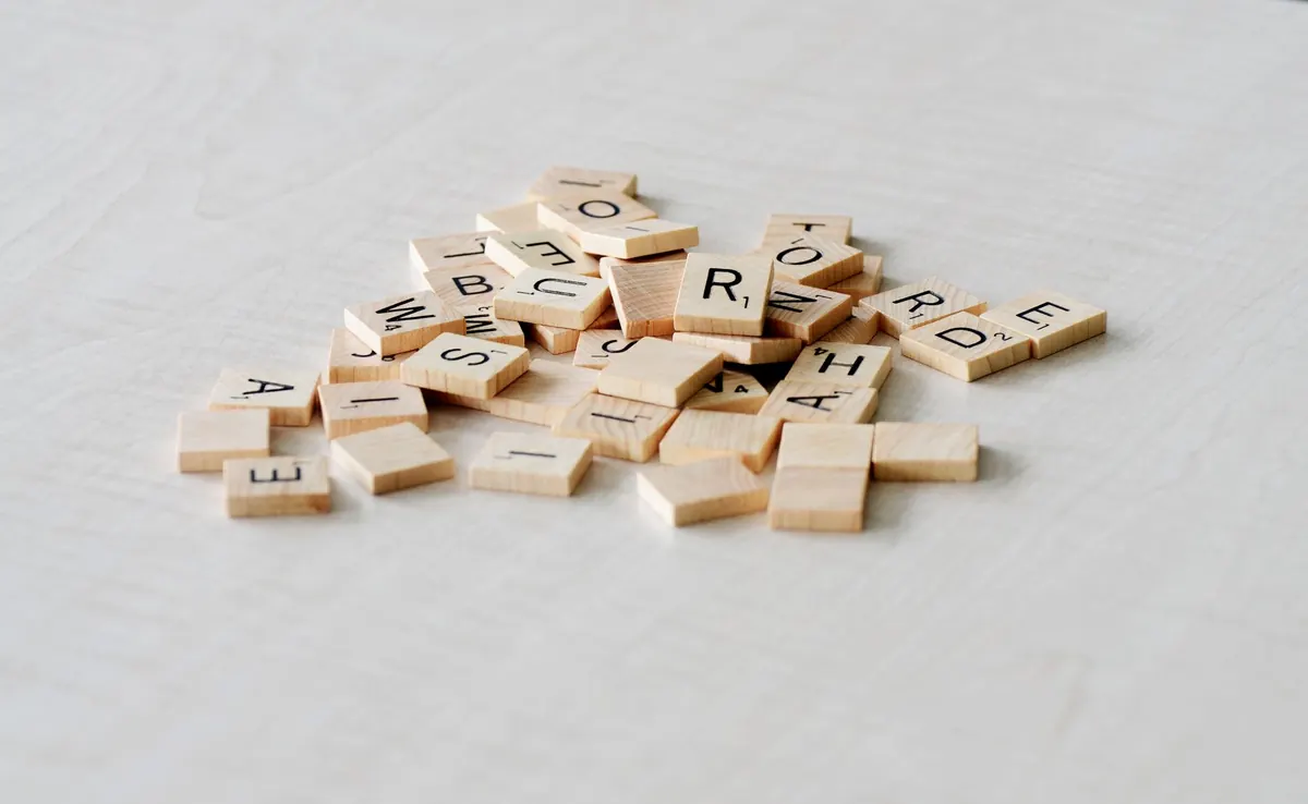 Close-up of wooden letter tiles scattered on a light table surface, ideal for word games.